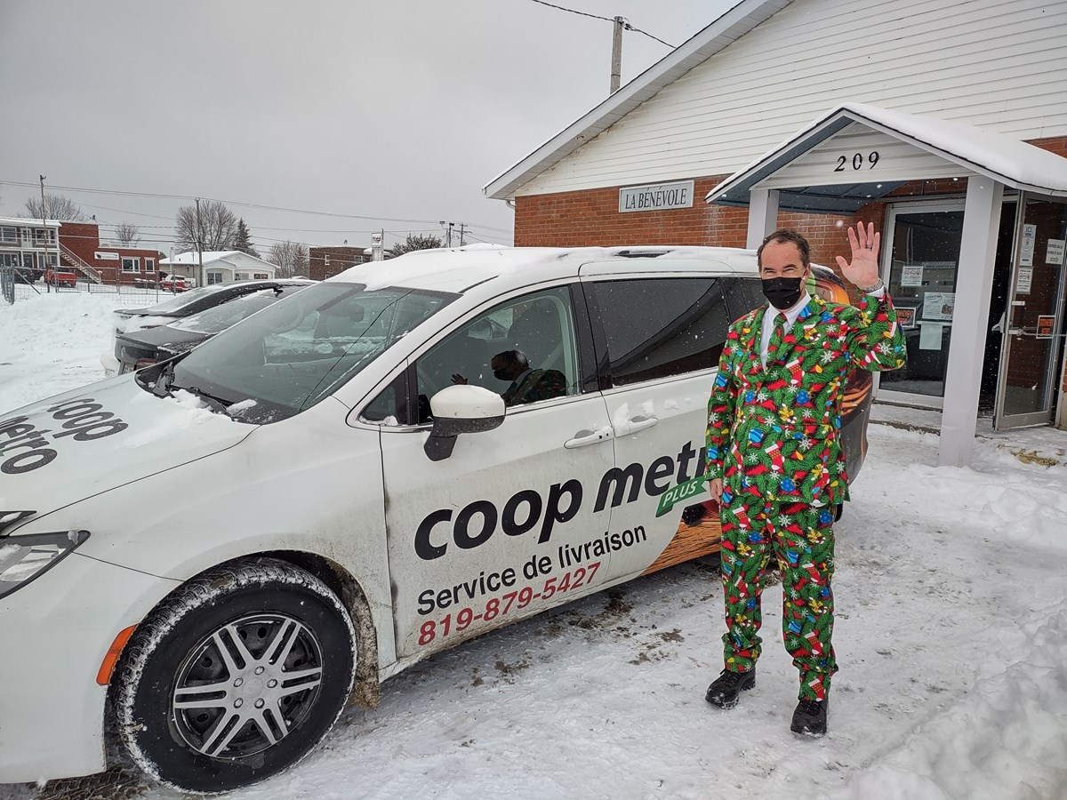 M. Yvan Fortier, bénévole, posant devant le véhicule, généreusement prêté par Coop Métro Plus pour la journée de distribution des paniers de Noël.